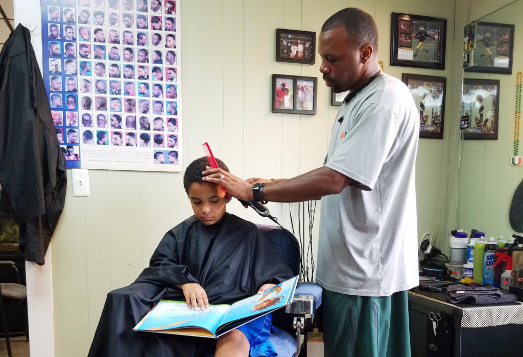 Jozef Jason, 7, reads a book to Ryan Griffin at the Fuller Cut in Ypsilanti, Mich. as part of the barbershop's literacy program.