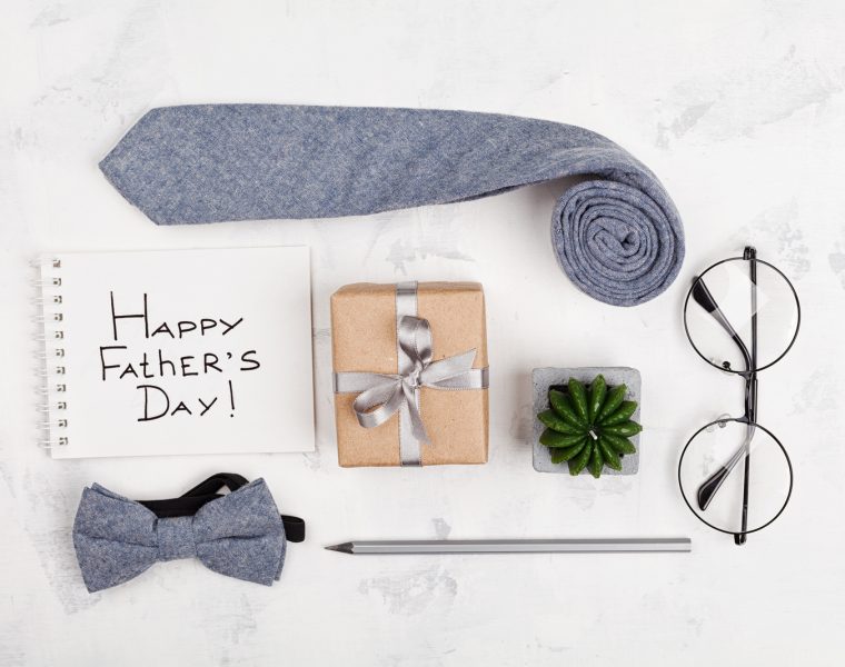 Composición de regalos para el Día del Padre que incluye una pajarita, gafas y una caja envuelta, como ideas originales para sorprender a papá.