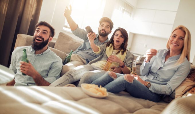 Amigos jóvenes viendo un partido de fútbol en la televisión.