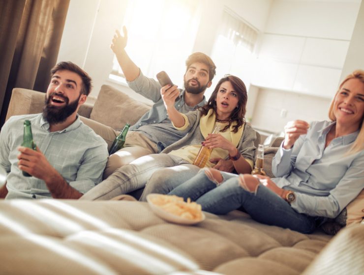 Amigos jóvenes viendo un partido de fútbol en la televisión.