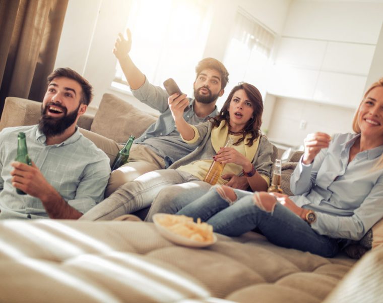 Amigos jóvenes viendo un partido de fútbol en la televisión.