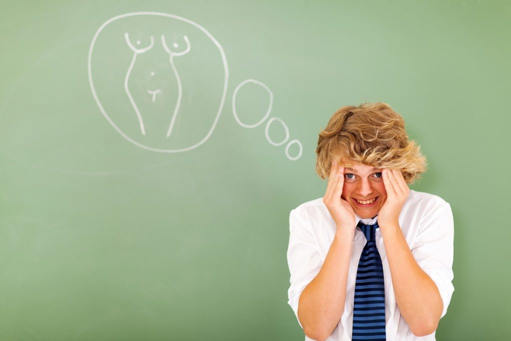 Adolescente en clase de educación sexual con expresión de incomodidad frente a un dibujo en el pizarrón.