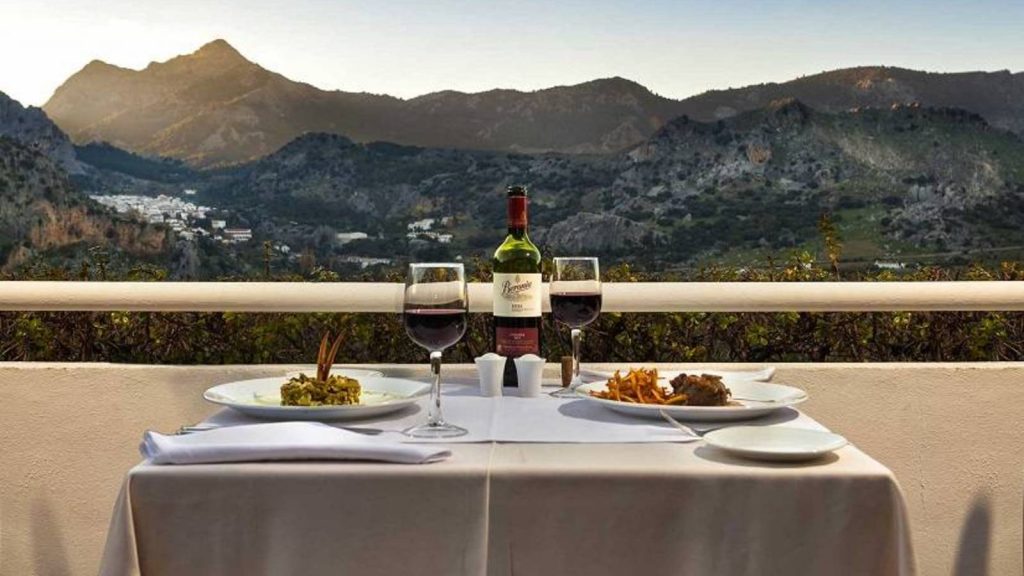 Mesa con vino tinto y cena al aire libre con vista a las montañas