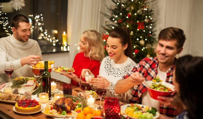 Familia celebrando la cena de Navidad con comida tradicional y decoración festiva.