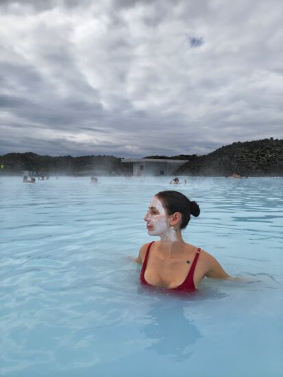 Mujer sumergida en un lago en Finlandia, tomando un baño caliente con máscara de crema en el rostro