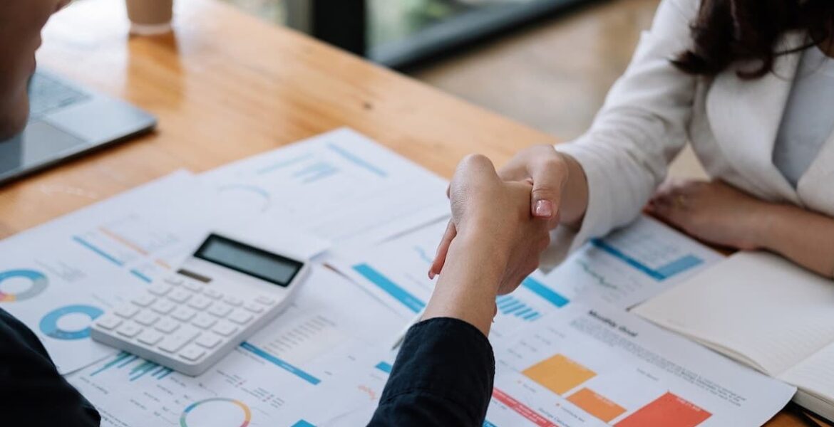 Persona estrechando la mano en una reunión laboral para negociar aumento de sueldo.