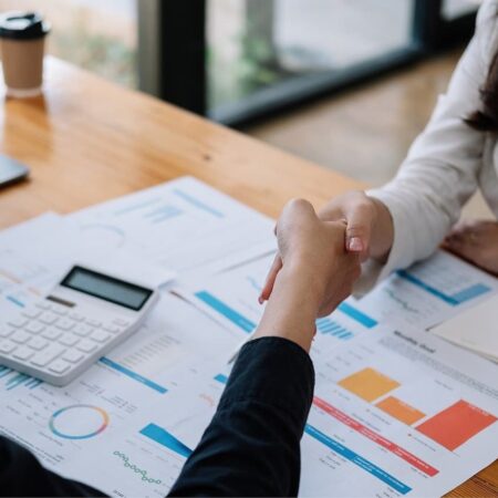 Persona estrechando la mano en una reunión laboral para negociar aumento de sueldo.