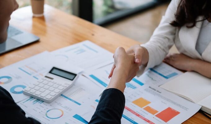 Persona estrechando la mano en una reunión laboral para negociar aumento de sueldo.