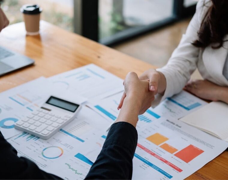 Persona estrechando la mano en una reunión laboral para negociar aumento de sueldo.
