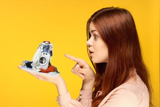 foto ilustración de una mujer con una pequeña lavadora en su mano repleta de ropa