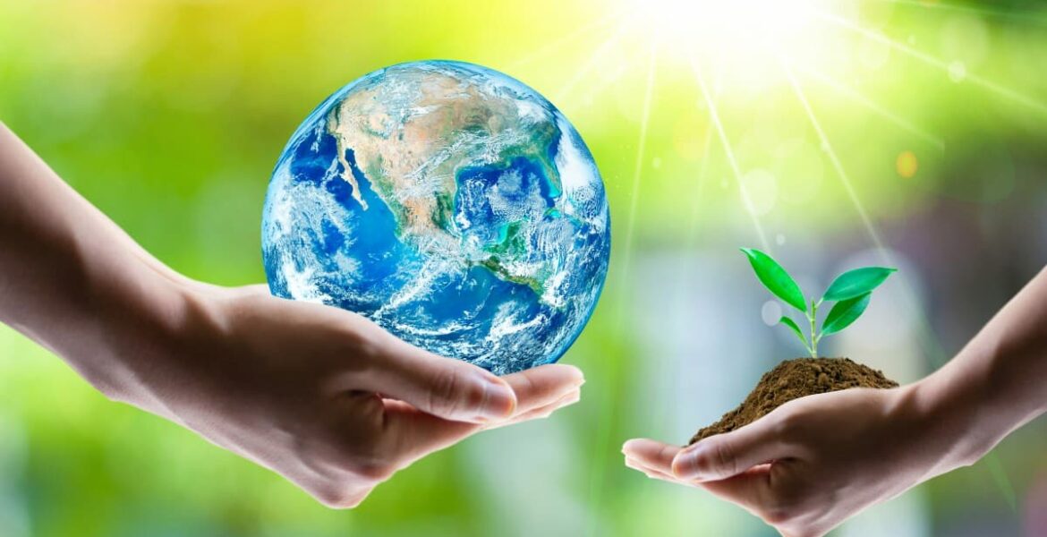 Manos sosteniendo la Tierra y un brote verde como símbolo de innovación en agronegocios.