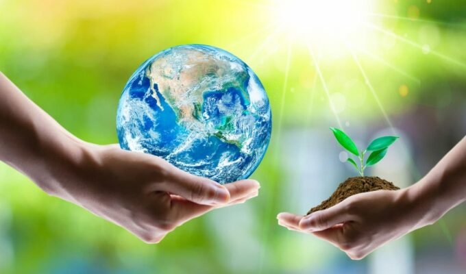 Manos sosteniendo la Tierra y un brote verde como símbolo de innovación en agronegocios.