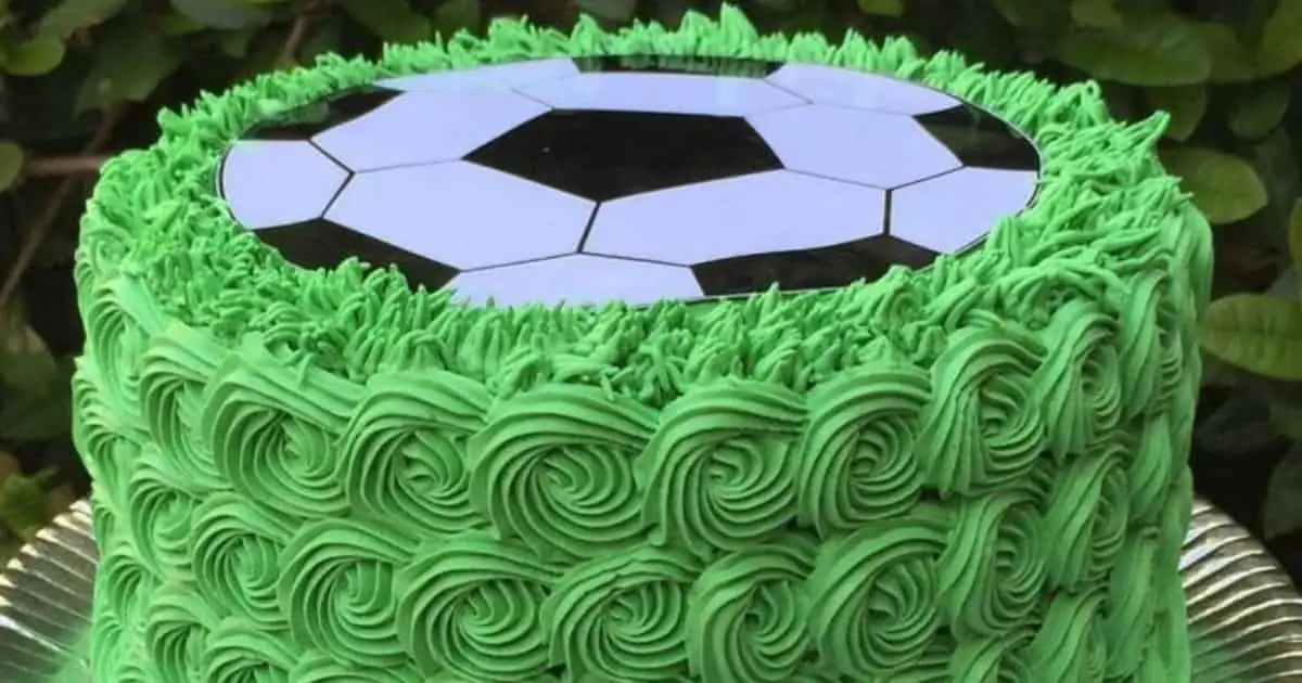 Pastel de futbol soccer con borde de glaseado verde y balón en la parte superior