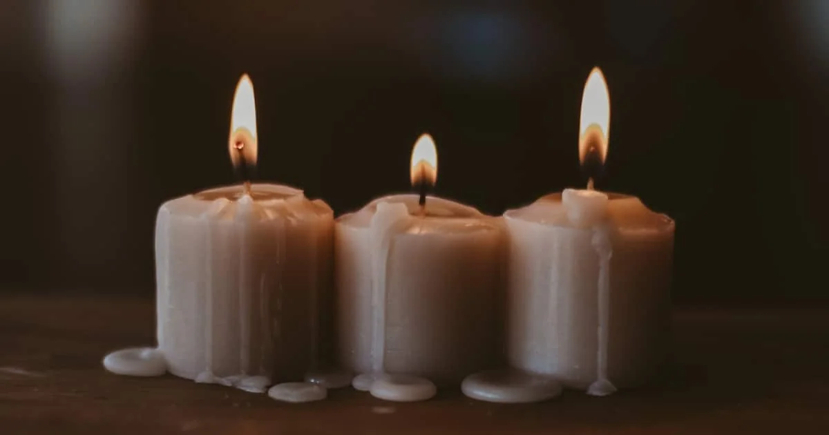 Tres velas blancas encendidas con la cera derretida goteando por los lados