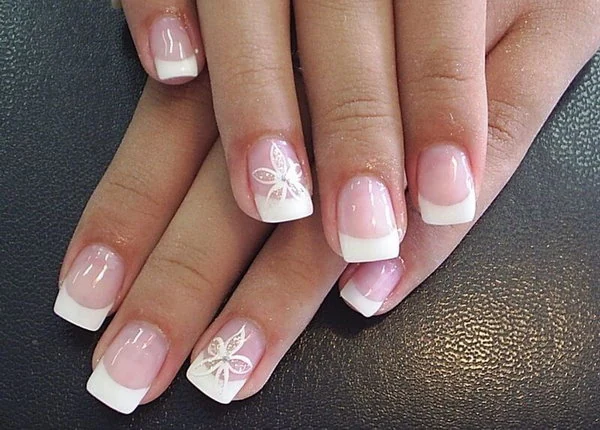 Diseño de Uñas Francesas Decoradas con Flores. Manicura francesa clásica con punta blanca y una delicada flor con brillantes como diseño en la uña de acento.
