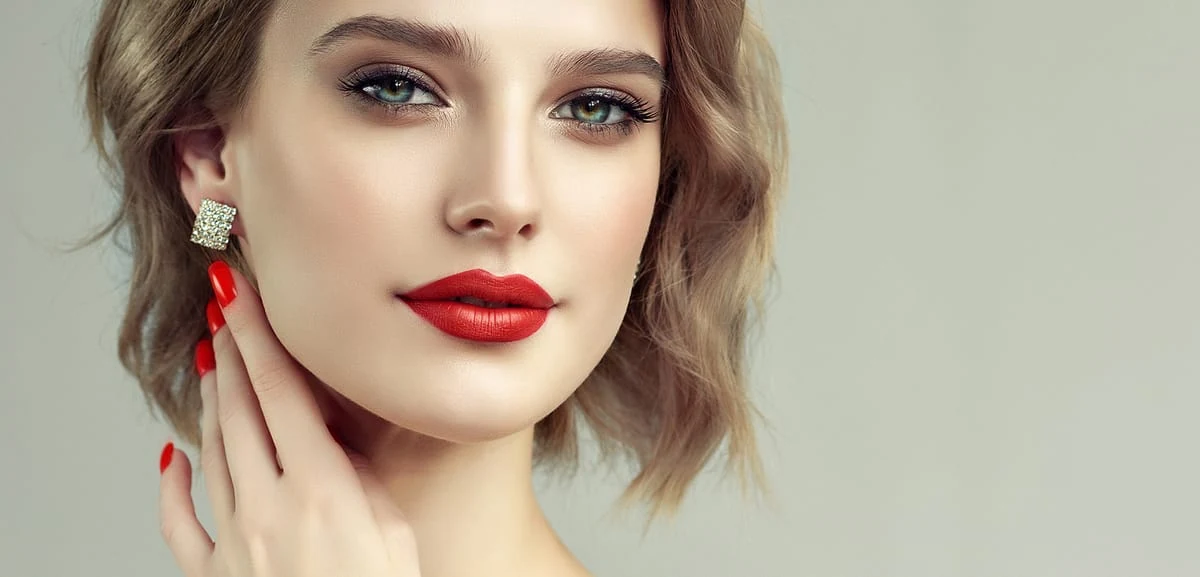 Una buena base de maquillaje es clave para el make up posterior de ojos y boca. Mujer joven elegante y maquillada con ojos bien destacados y labios rojos