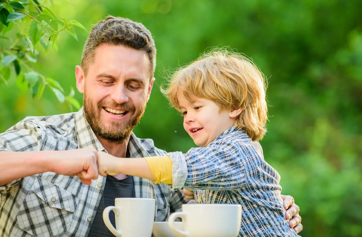 Padre e hijo sonrientes chocando los puños (fist bump) en una celebración del Día del Padre, simbolizando su complicidad y vínculo.