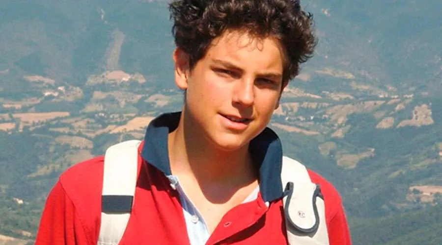 Foto de Carlos Acutis en un paisaje montañoso.