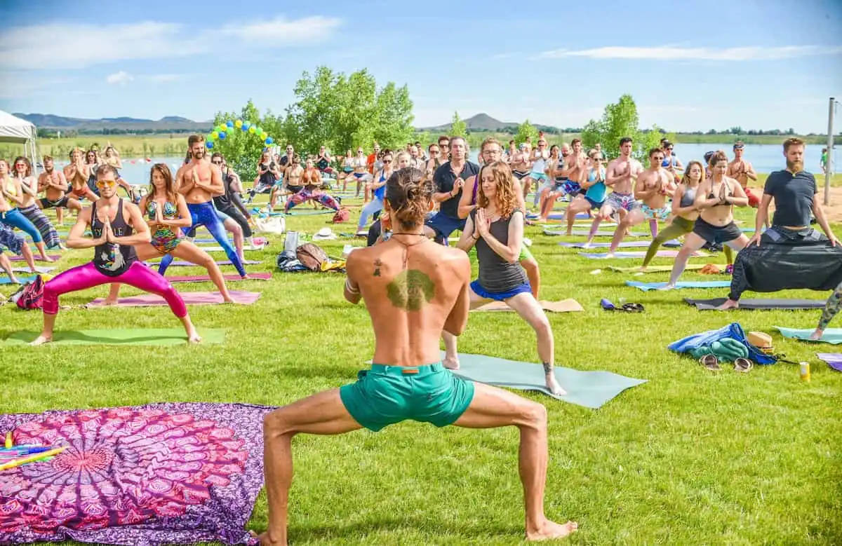 Grupo de personas practicando yoga al aire libre durante un evento Daybreaker al amanecer.