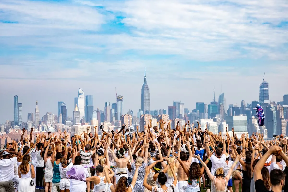 Fiesta Daybreaker al amanecer en Nueva York con gente bailando y celebrando bajo el sol.