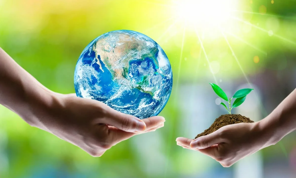 Manos sosteniendo la Tierra y un brote verde como símbolo de innovación en agronegocios.