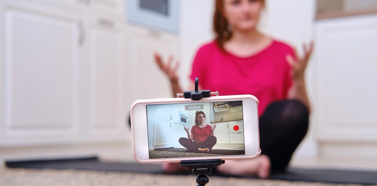 Un celular en un trípode grabando a una creadora de contenido, listo para ser editado con una app para principiantes como Canva o CapCut.