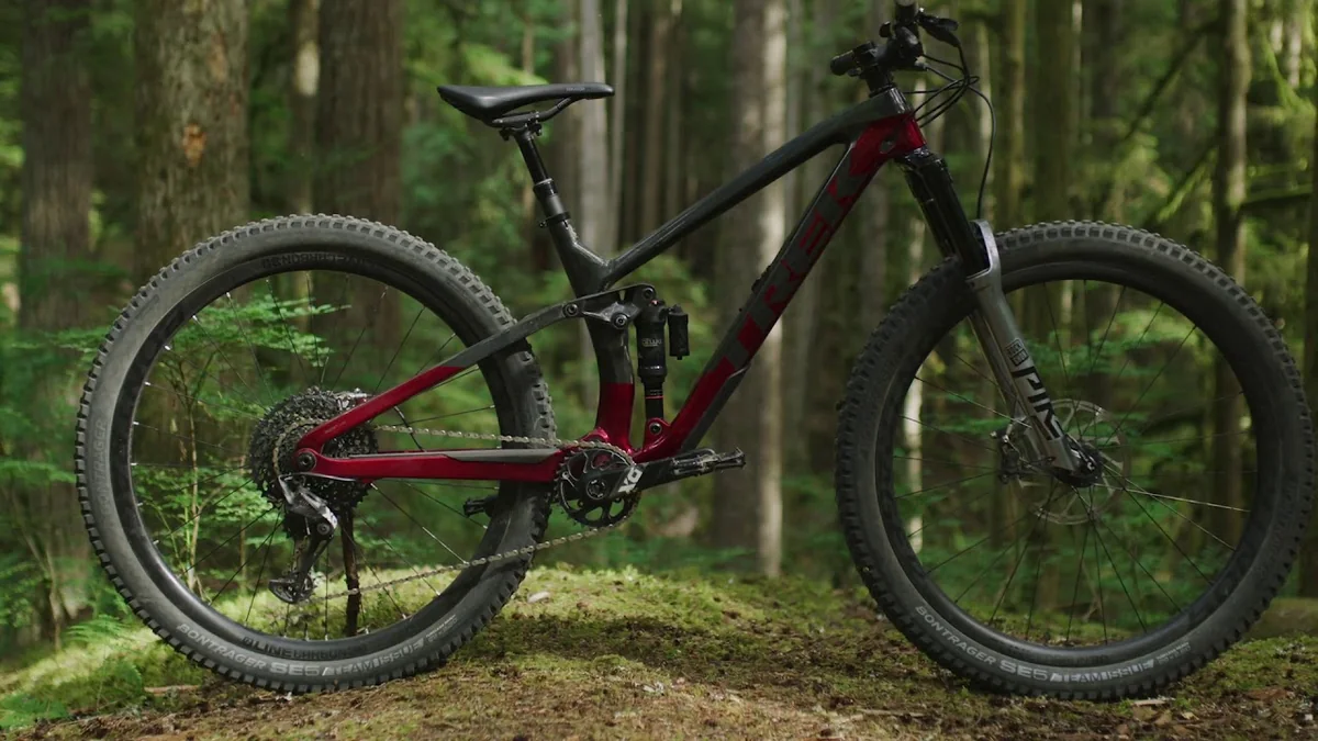 La bicicleta de montaña Trek Fuel EX 9.8, uno de los modelos de MTB para trail recomendados para 2025, en un sendero mostrando su cuadro de carbono y doble suspensión.