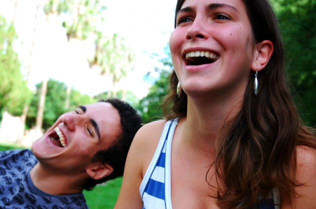 Dos jóvenes riendo al aire libre, disfrutando de un momento de alegría y conexión.