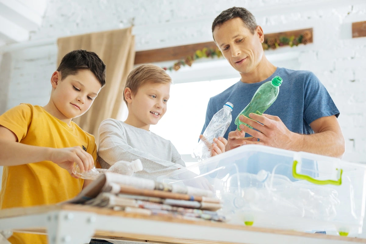 Cómo Enseñar a los Niños a Reciclar en Familia Enseñando cómo separar residuos y reciclar botellas de plástico en un contenedor en casa.