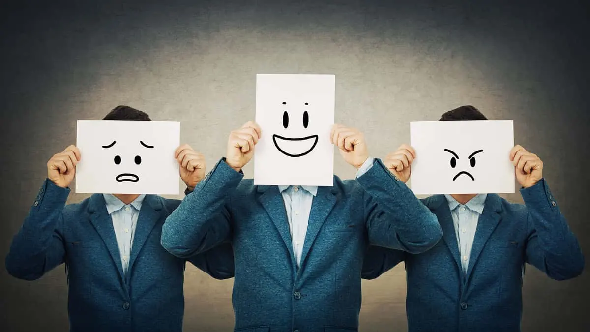 Imagen de 3 hombres con un cartel con caritas con distintas expresiones emocionales