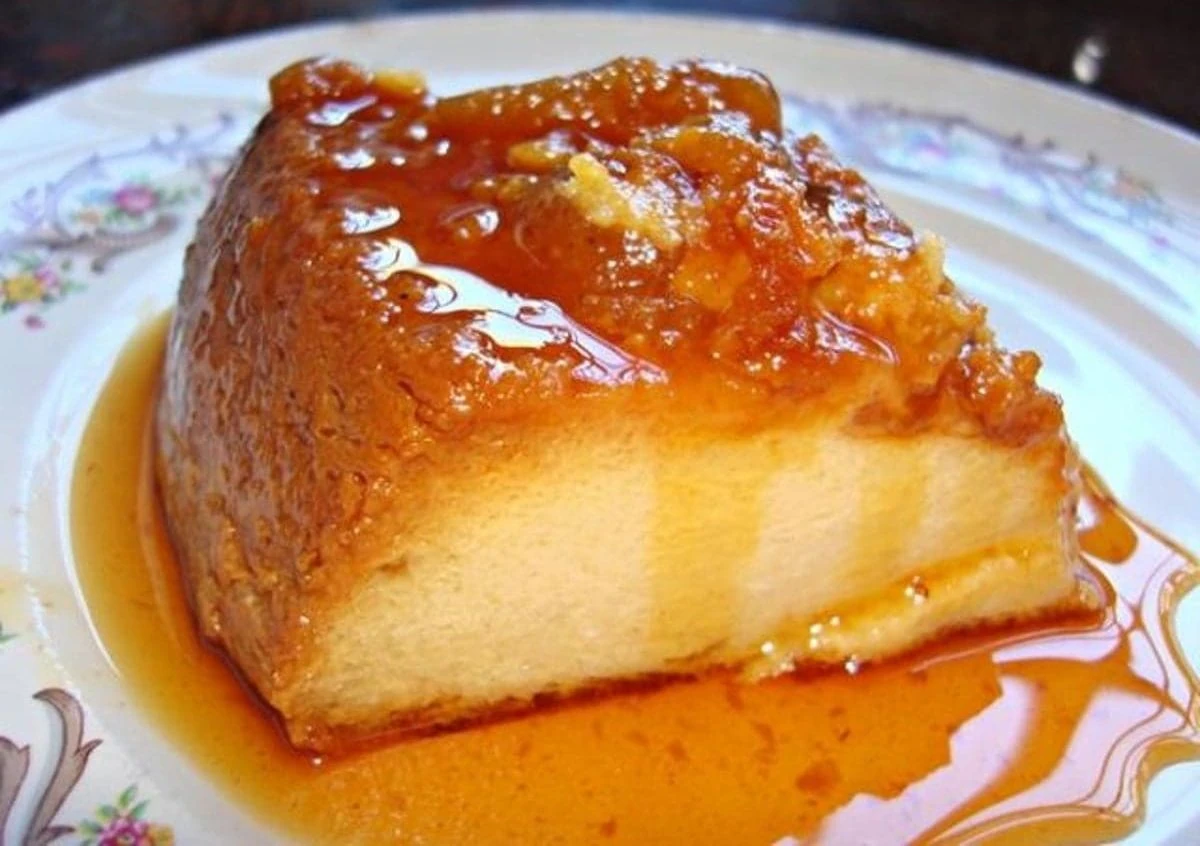 La Receta de Flan de la Abuela que Nunca Falla. Porción de un cremoso flan napolitano casero bañado en una abundante salsa de caramelo dorado, listo para comer.