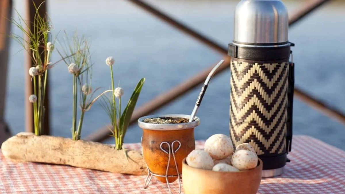 Merienda de mate, pan, chipa en una mesa al costado del río