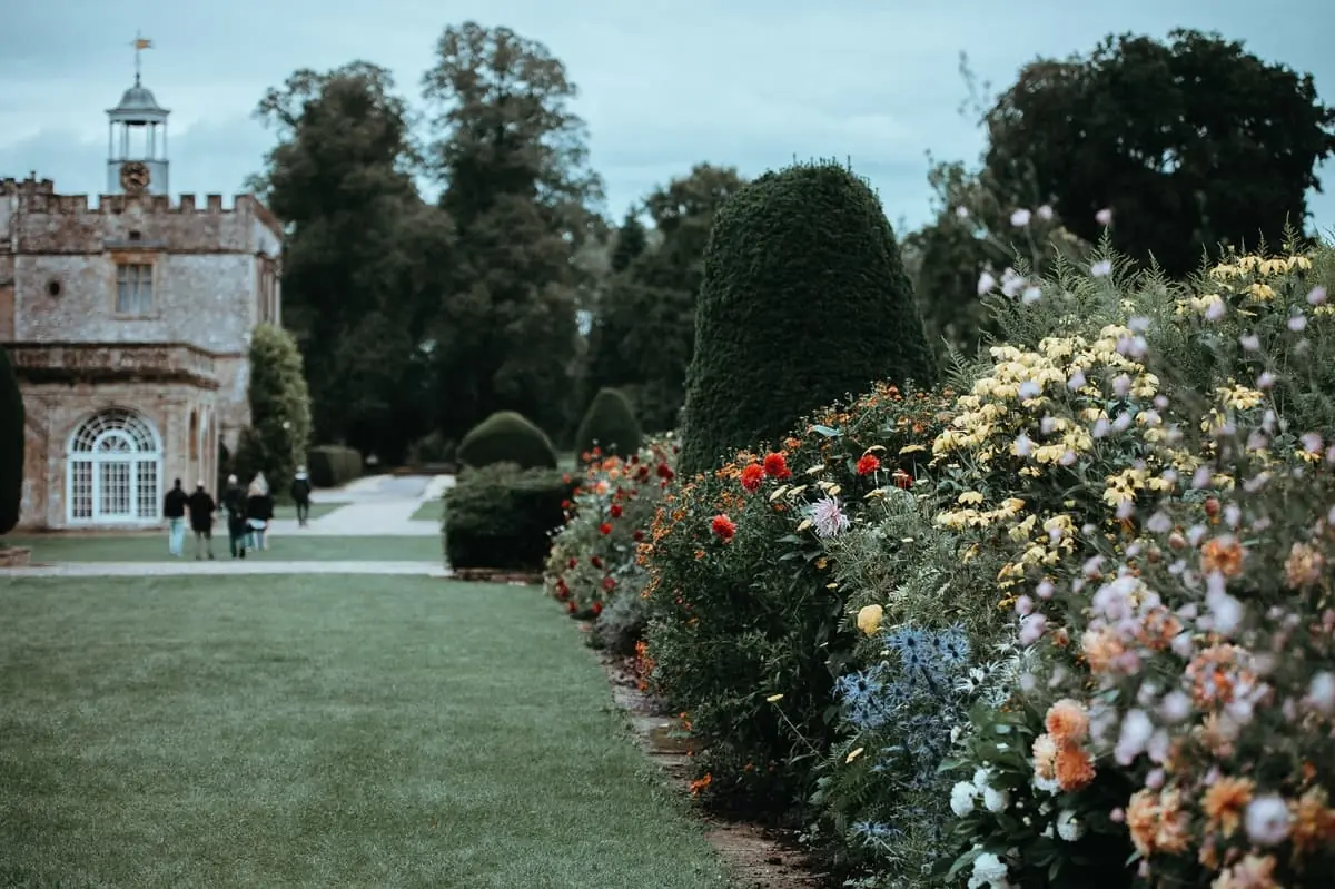 Parterre de jardín señorial con arbustos podados y flores Jardín histórico con topiarios y setos de arbustos florales frente a mansión