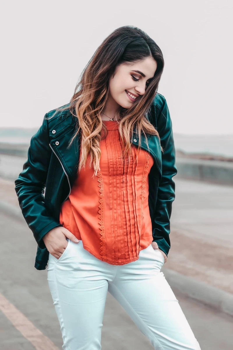 Look moderno al combinar un pantalón blanco con una blusa color coral y chamarra de piel negra. Outfit perfecto para una salida casual.