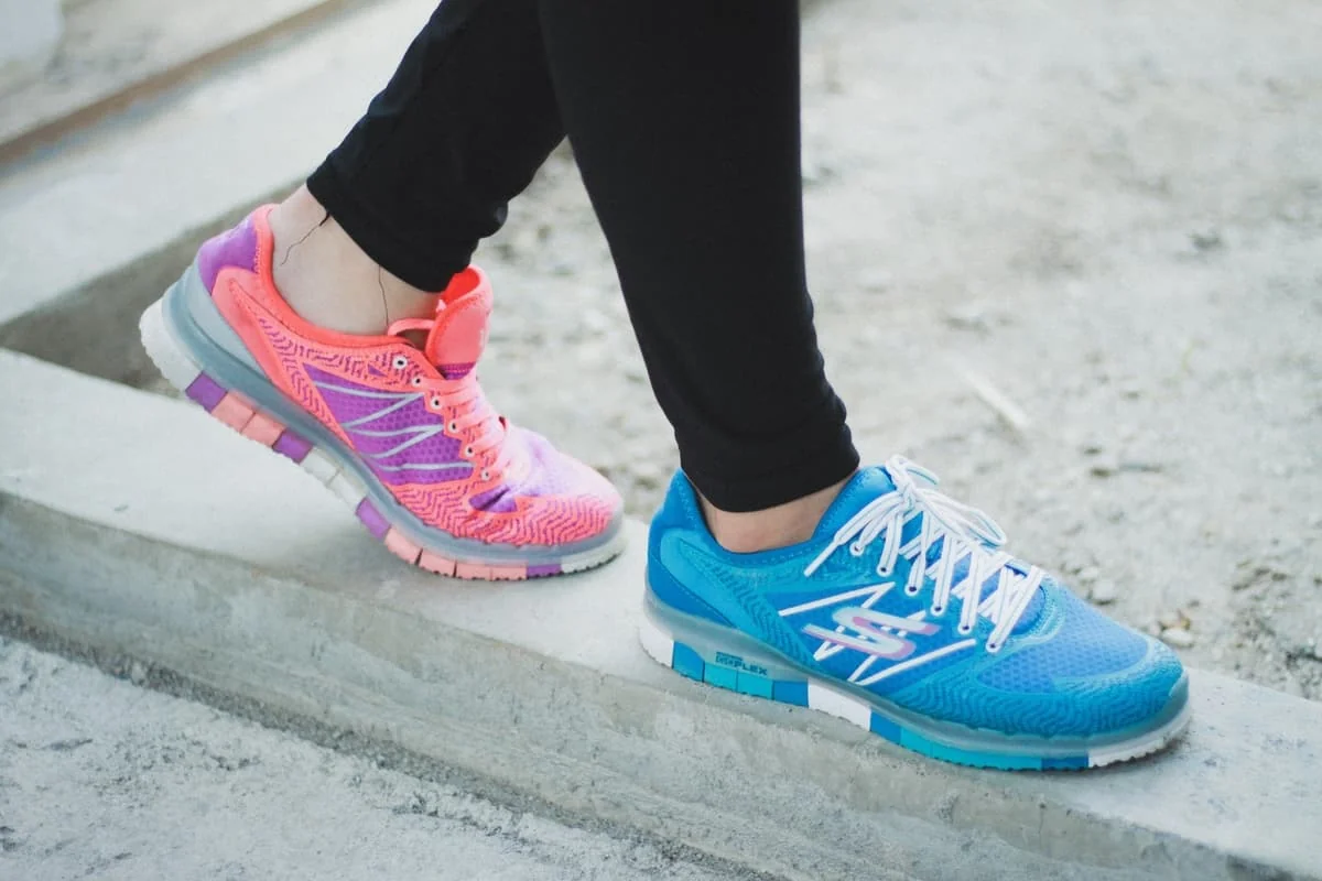 Zapatillas deportivas de colores en uso sobre una superficie de cemento.
