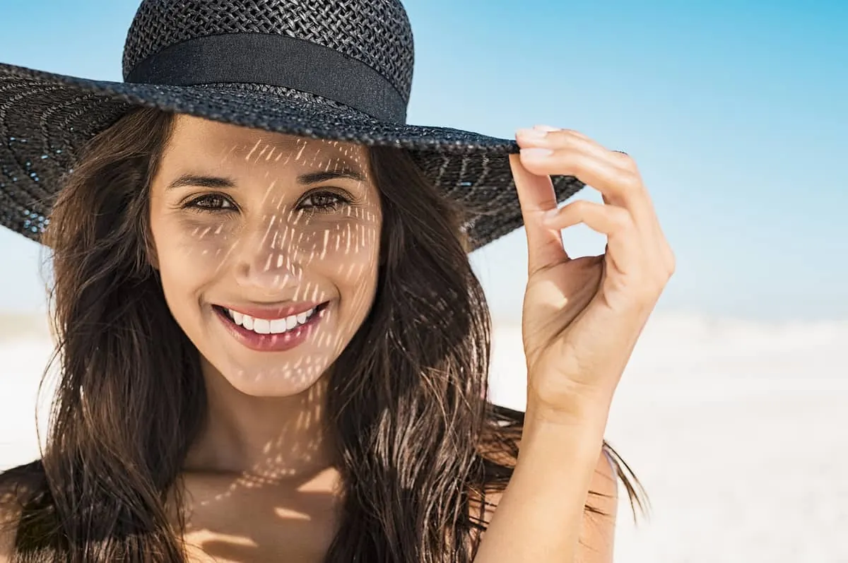 Mujer joven usando un tipo de sombrero negro muy moderno para protegerse del sol
