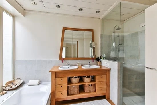 Decoración de baño moderno chico con mueble de madera clara estilo abierto, doble lavabo blanco y espejo grande para ampliar el espacio visualmente.
