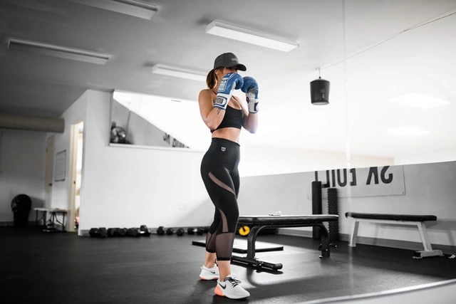 Entrenamiento de boxeo guiado en casa con YouTube Mujer entrenando boxeo en un gimnasio con guantes, ejemplo de rutinas que puedes seguir en YouTube