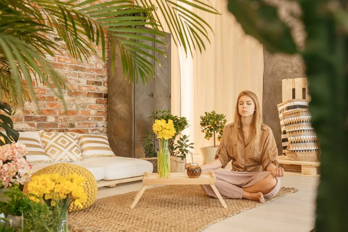 Mujer meditando sentada en una alfombra mientras toma mate