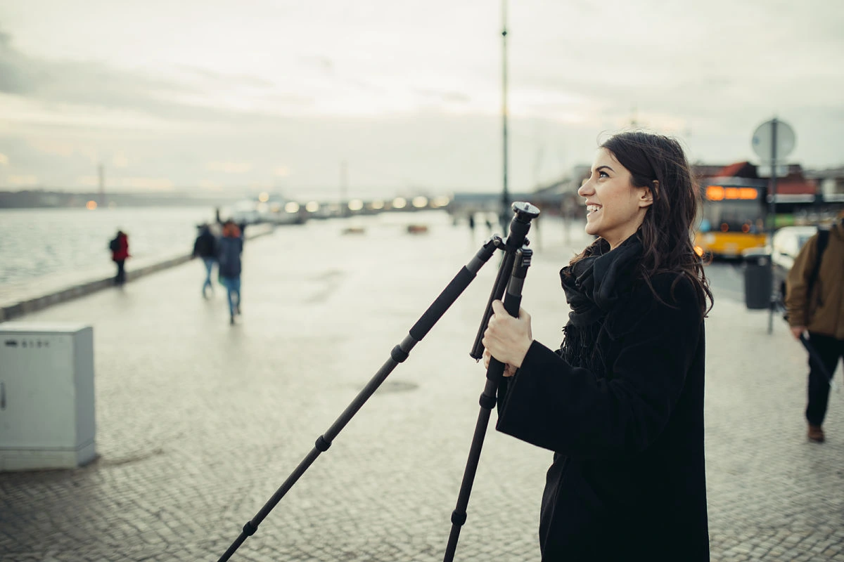 Creadora de contenido sonriendo con su trípode, lista para grabar un video que luego podrá editar fácilmente gracias a las nuevas herramientas para principiantes.