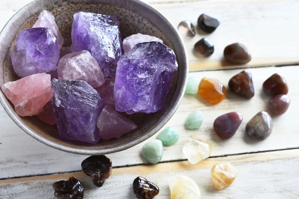 Cristales de amatista, cuarzo rosa y piedras energéticas sobre mesa blanca de madera.