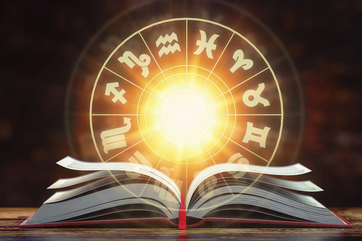 Libro abierto con símbolos zodiacales iluminados, representando el horóscopo y las predicciones astrológicas.