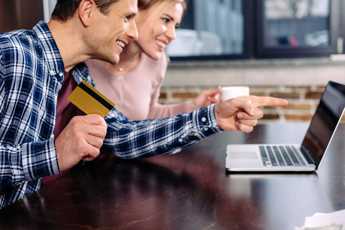pareja comprando en línea en su casa con su laptop mientras toma un café