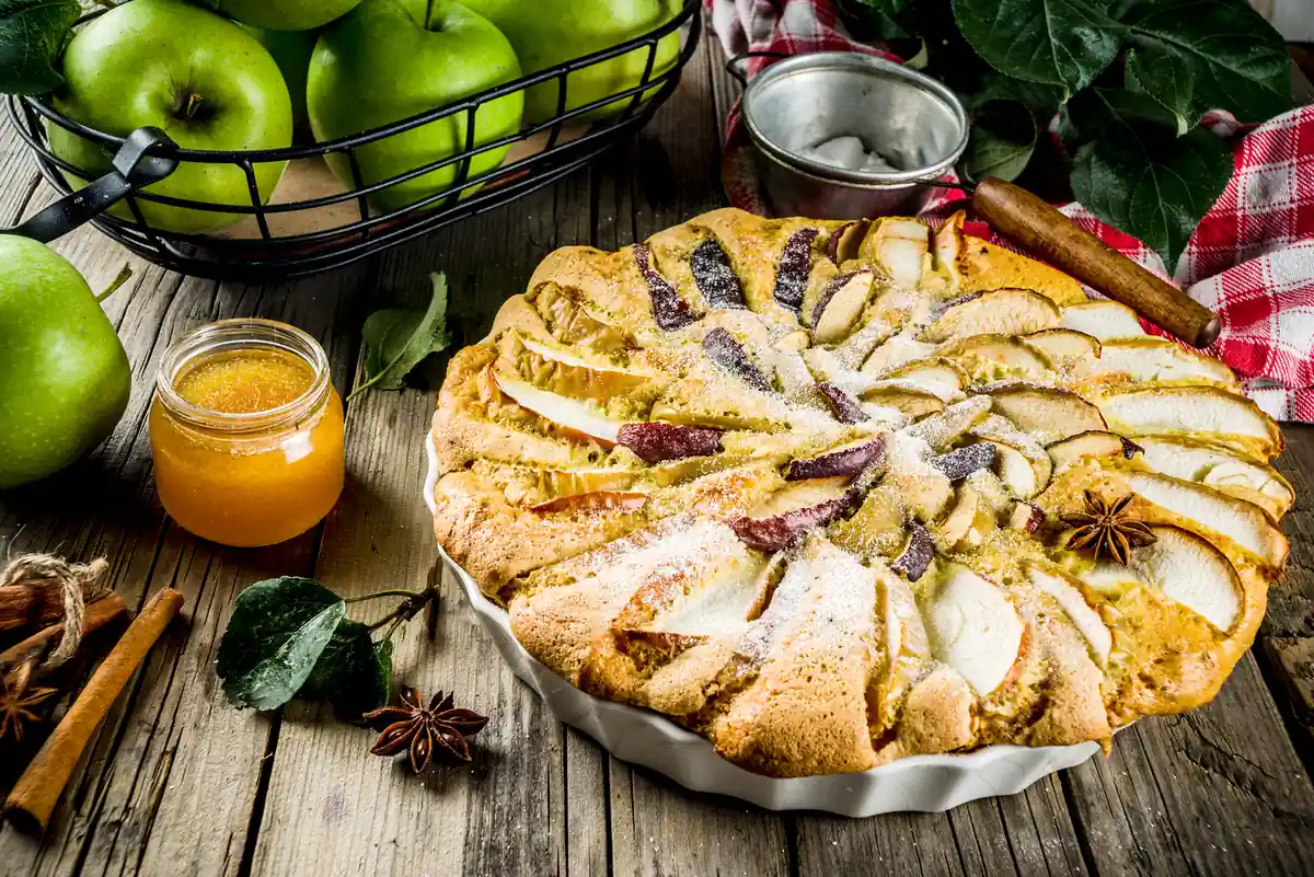 Tarta de manzana con canela y anís estrellado junto a manzanas verdes y miel