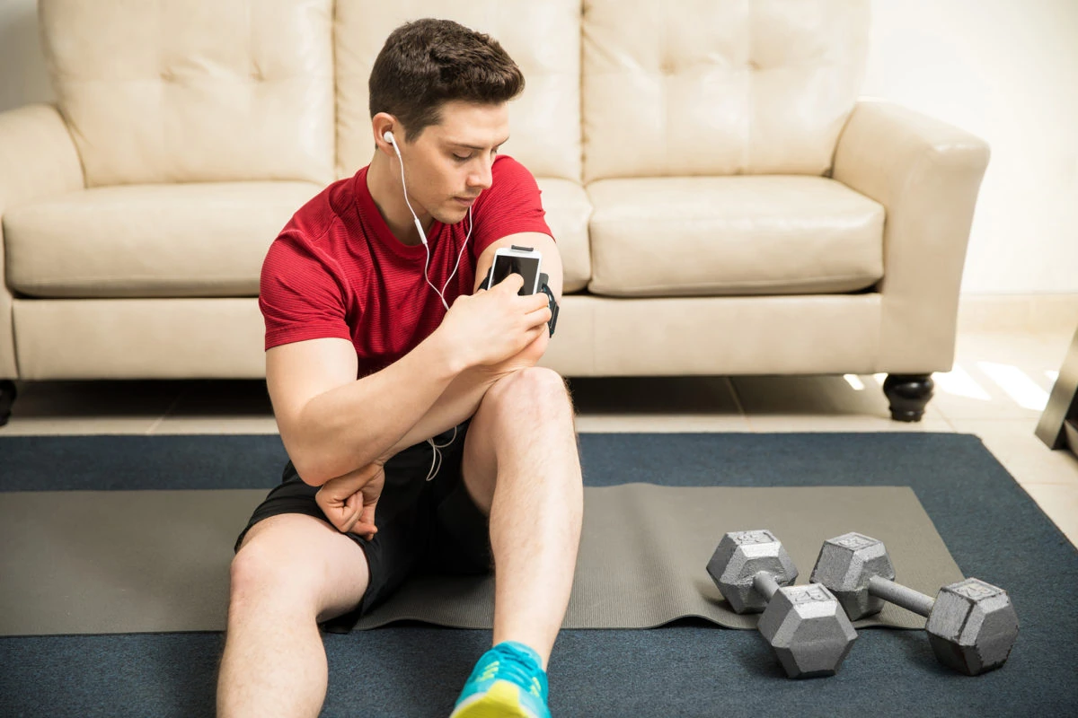 Las apps orientadas al bienestar están en auge. Hombre joven usando una app para entrenar en su casa