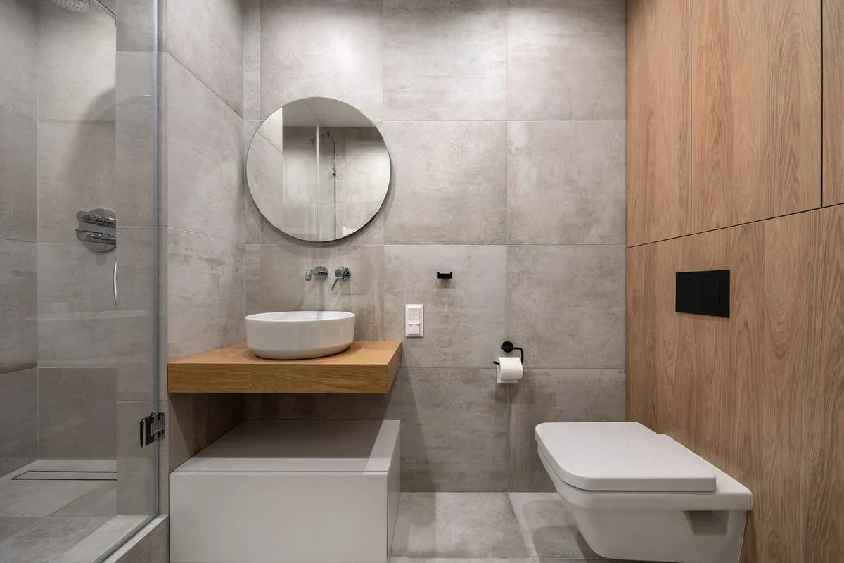 Baño moderno chico con ducha de vidrio y cerámicos grises