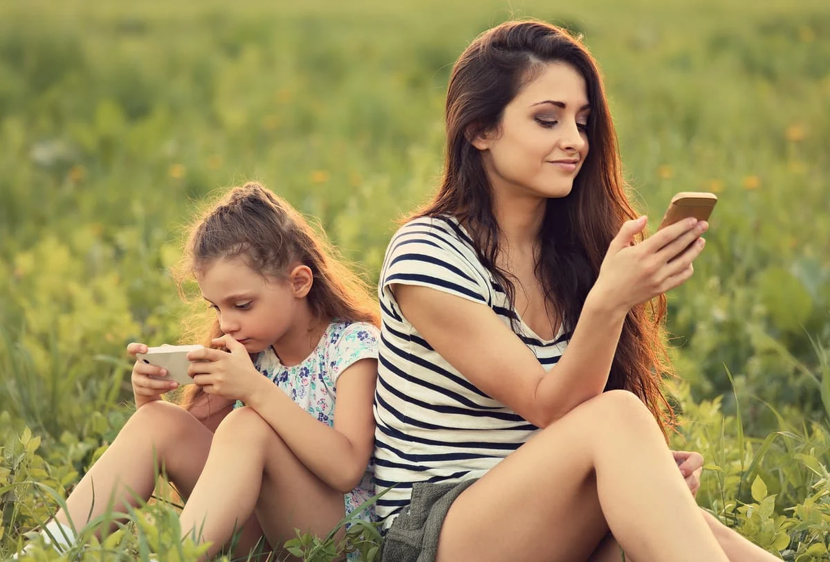 Mamá e hija mirando el telefono celular sin mirarse