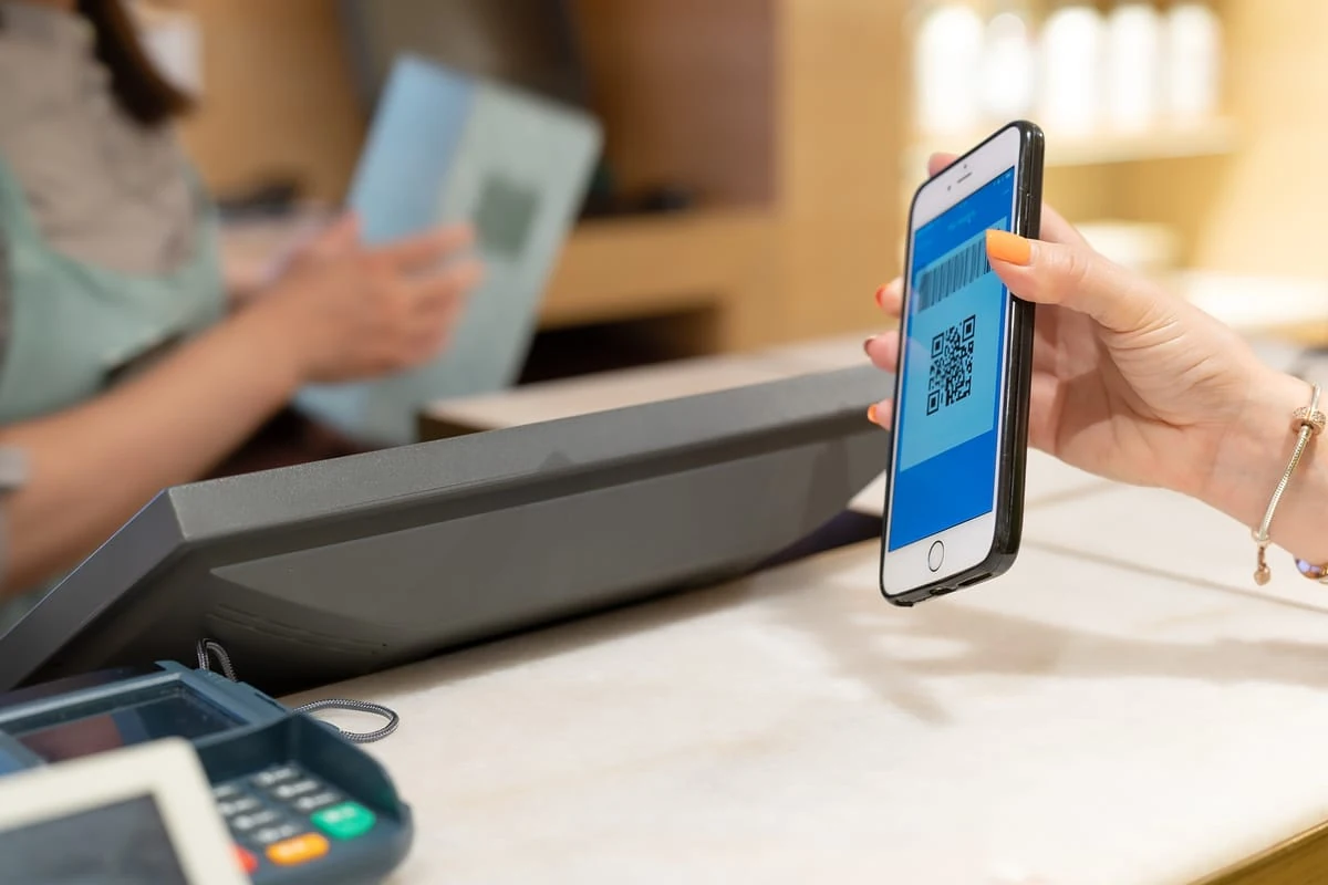 Las apps de reintegro permiten ahorrar mucho dinero por mes. mujer mostrando su teléfono con una app de reintegro al pagar