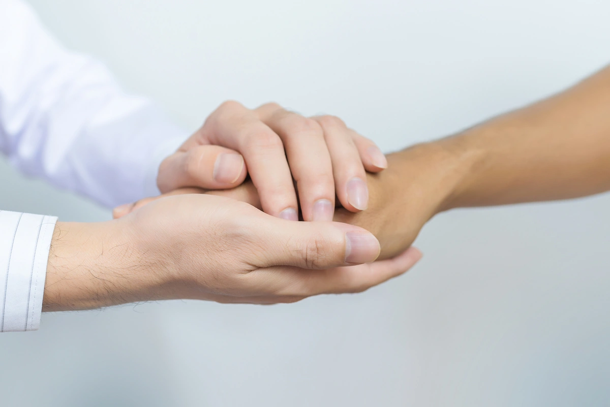 Dos manos sujetando con cariño otra mano en gesto de apoyo