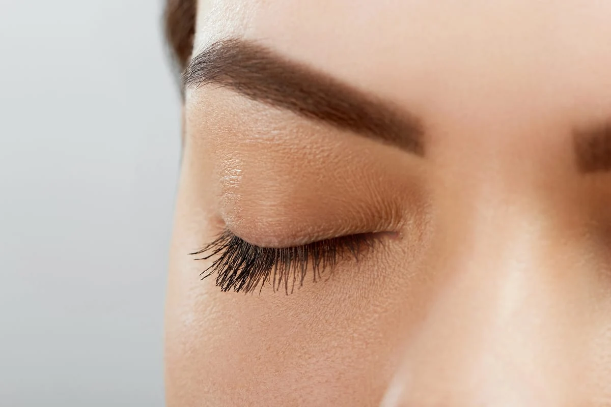 Mujer latina aplicando base de maquillaje con brocha frente al espejo